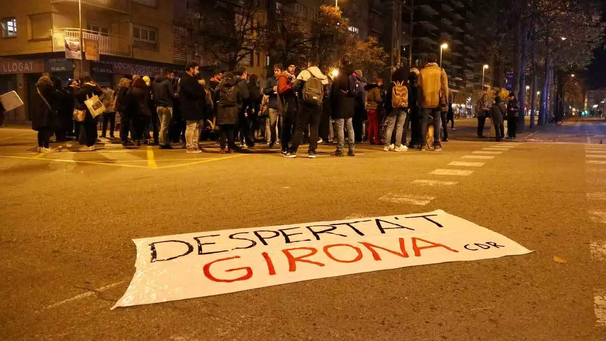 Els manifestants tallant el carrer de Barcelona i en primer pla una pancarta dels CDR 'Desperta't Girona'