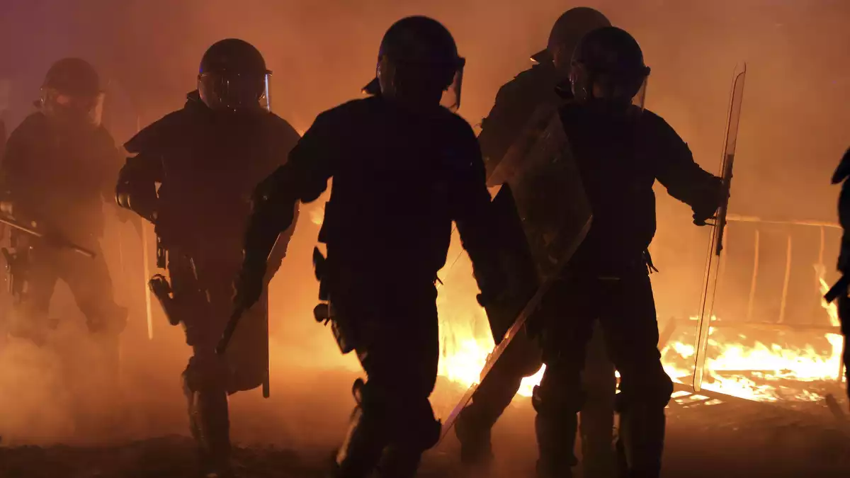 Agents de la Policia Nacional travessant les flames d'una barricada a la Plaça Urquinaona de Barcelona