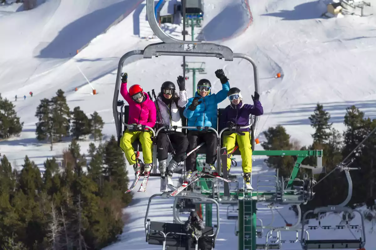 esquiadors al damunt d'un telecadira en marxa