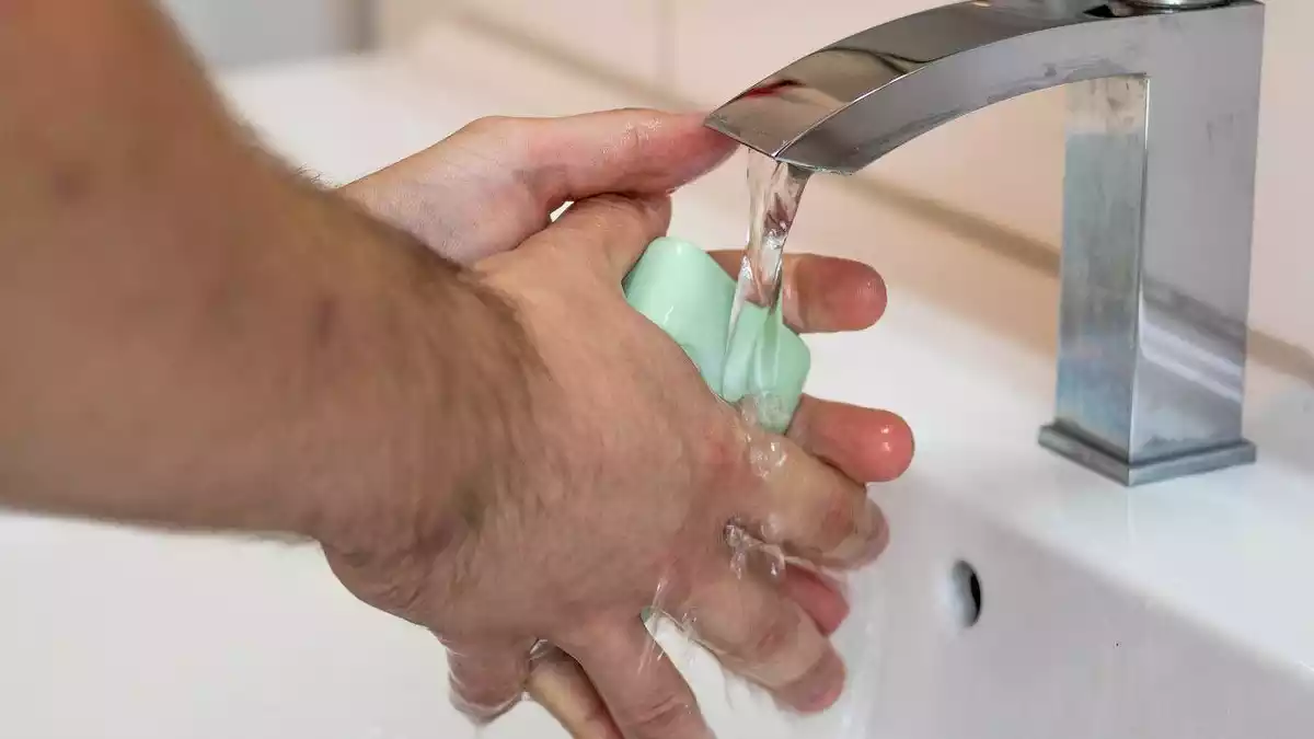 Home rentant-se les mans amb sabó