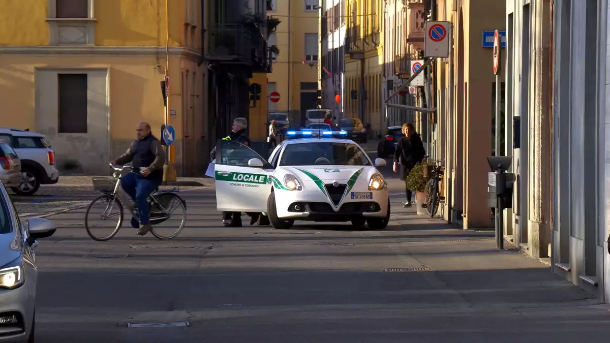 Un vehicle de la Policia Local italiana enmig del carrer amb un agent i 2 persones el 22 de febrer de 2020