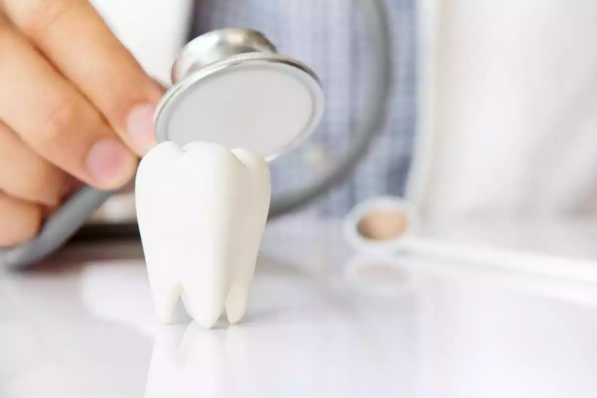 Detall d'una dent amb un metge auscultant