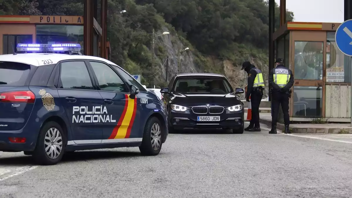Dos agents de la Policia Nacional fent un control en un turisme espanyol que vol creuar la frontera al Pertús el 17 de març de 2020.
