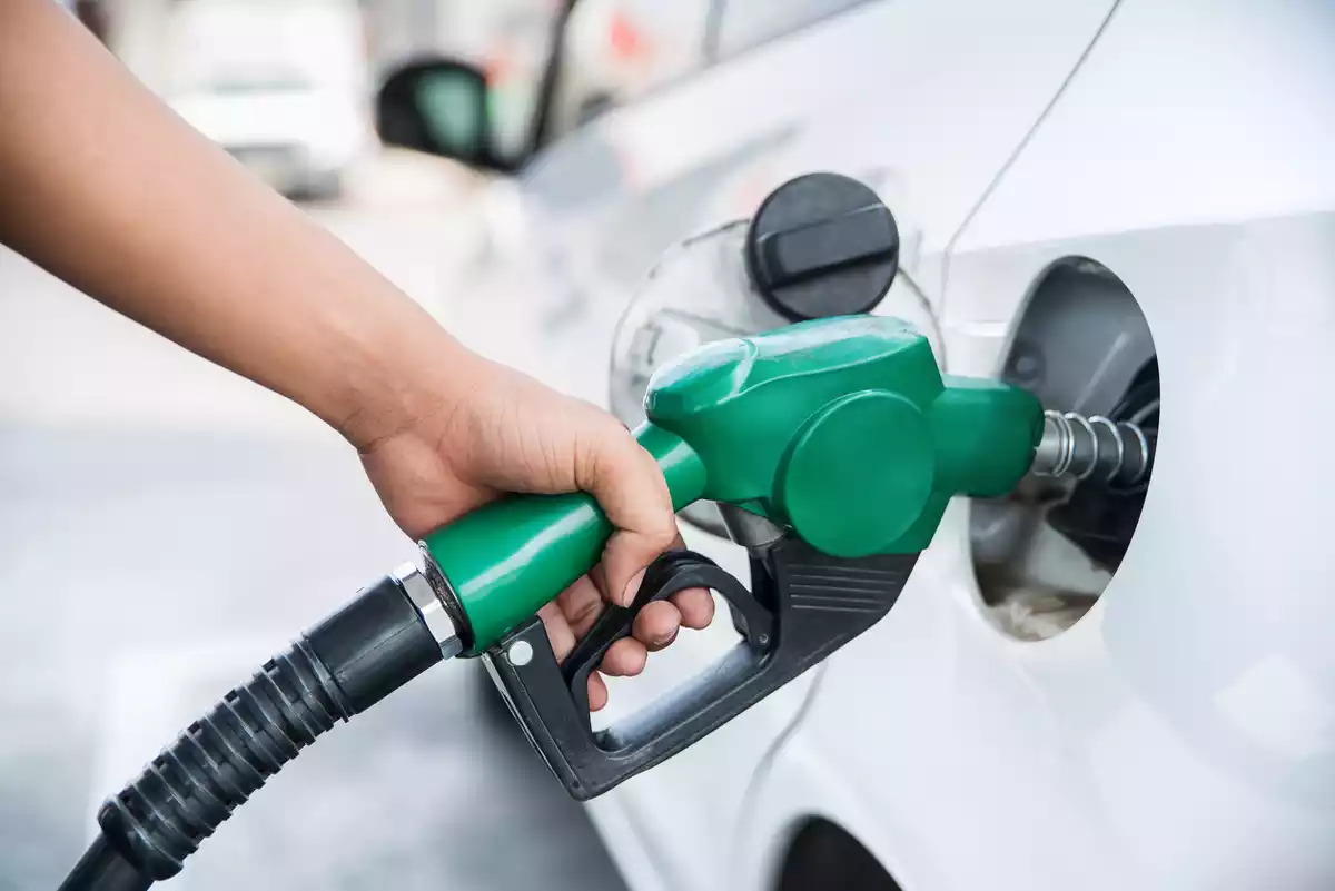 Una persona posant gasolina en un vehicle amb un sortidor de gasolinera