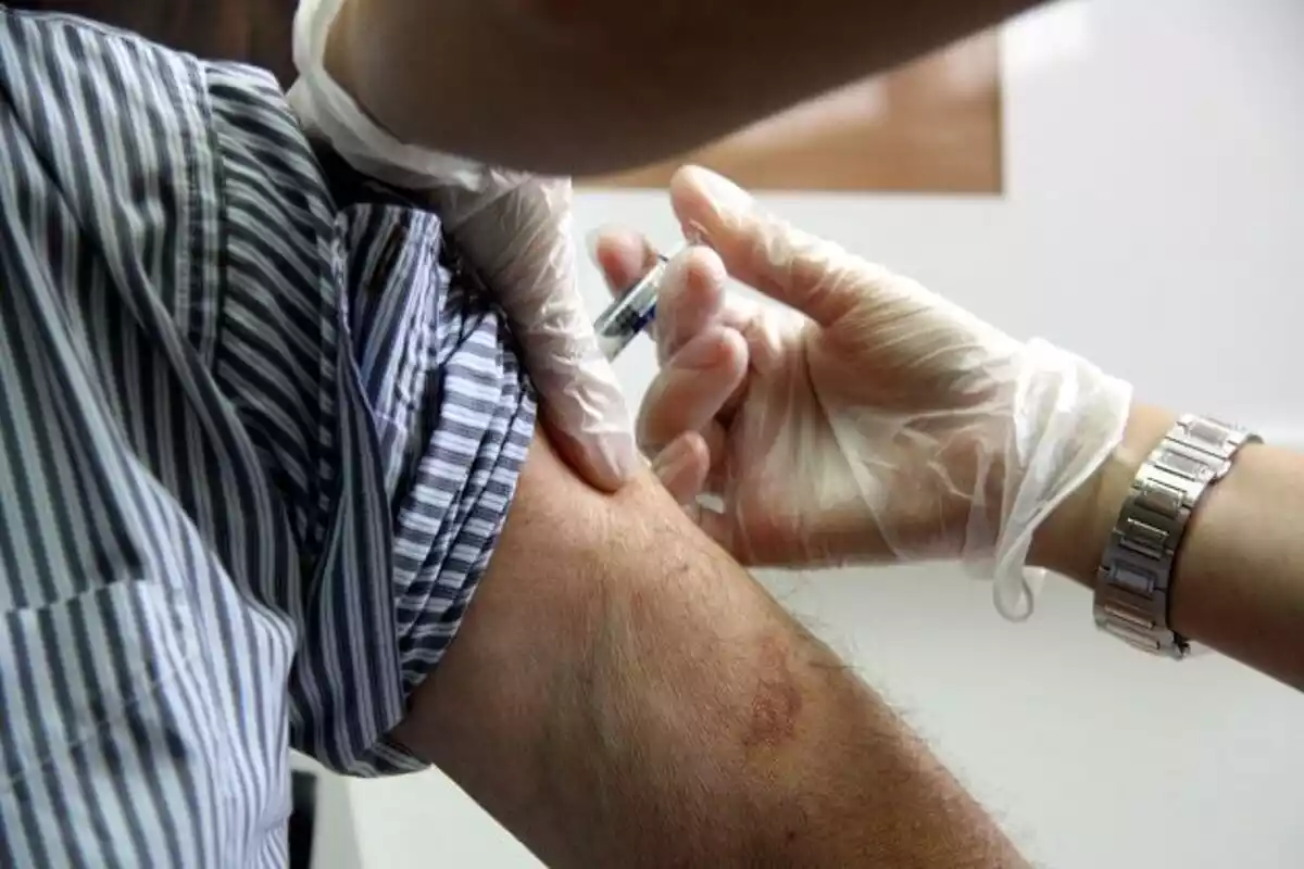 Personal sanitari posa una vacuna al braç d'un home