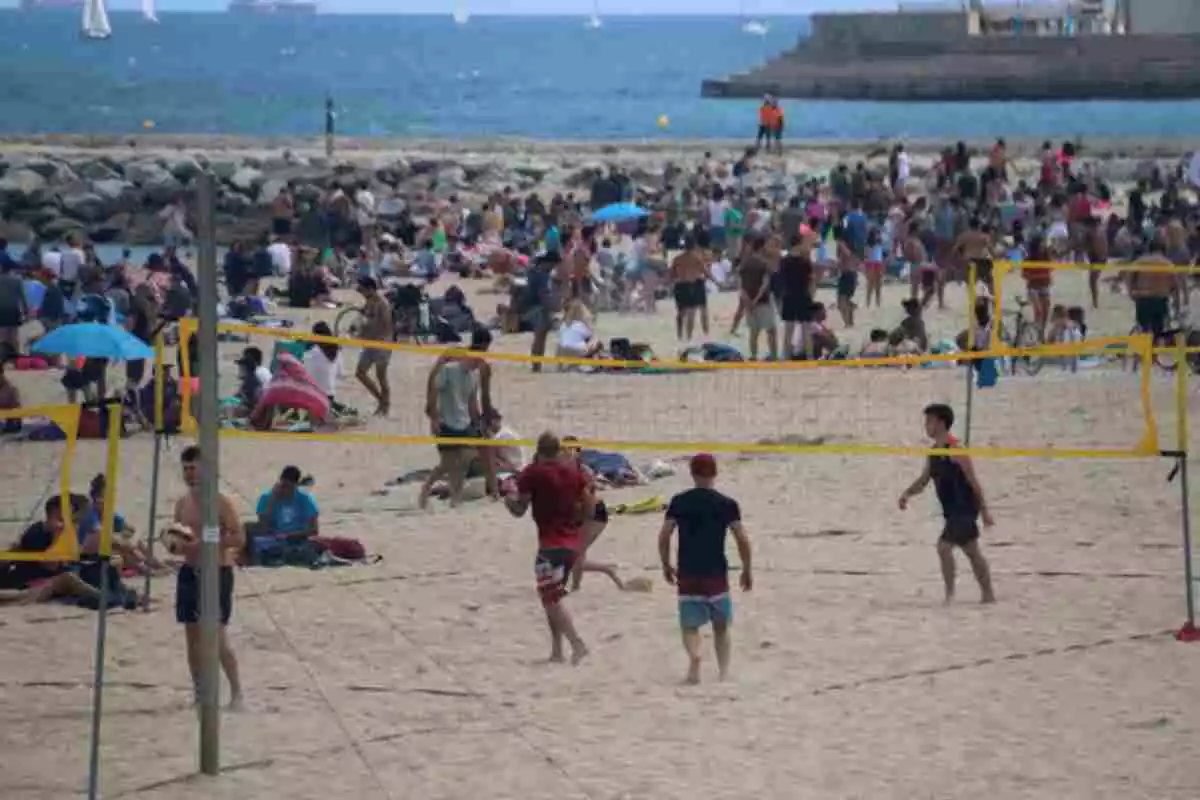 Una platja plena de gent a Barcelona amb un grup jugant en primer pla