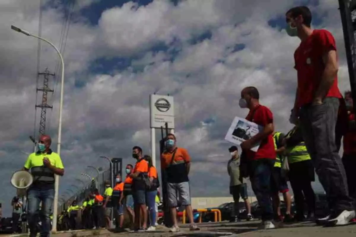 Diversos treballadors amb armilles grogues i taronges, davant la porta de Nissan a Barcelona