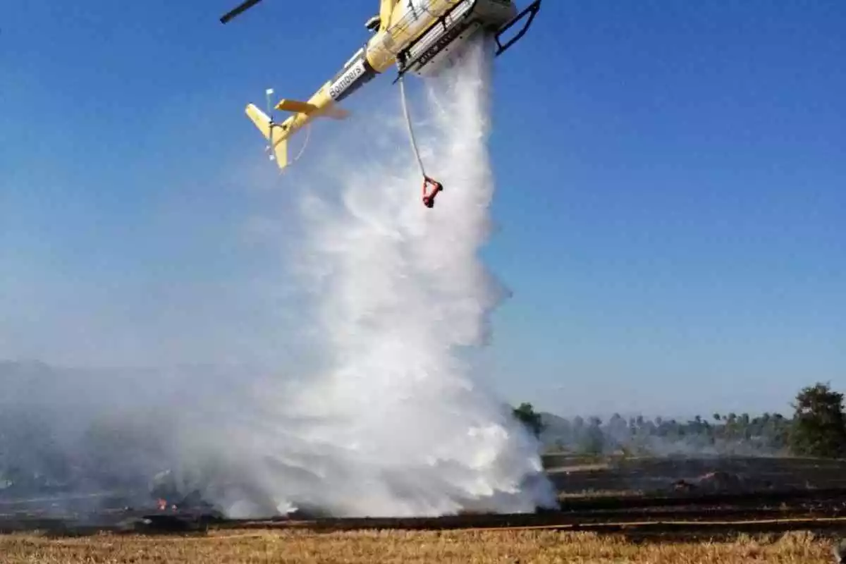 L'helicòpter dels Bombers llançant aigua per apagar el foc