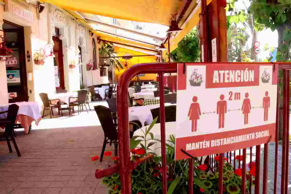 Imatge d'una terrassa d'un restaurant de Sitges, amb un cartell que demana mantenir la distància social, 17/07/2020
