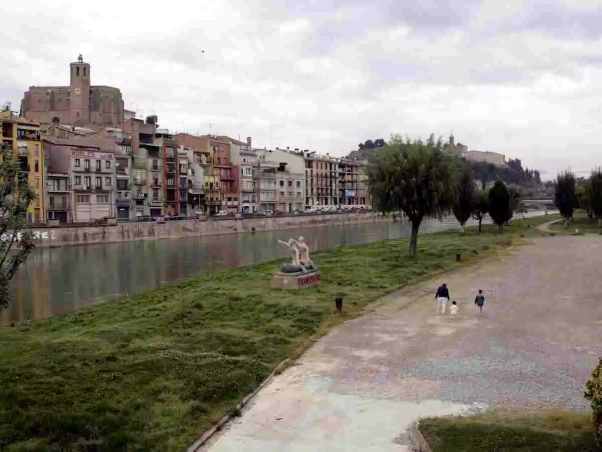 Pla general d'un pare passejant amb els seus dos fills a la zona del riu de Balaguer