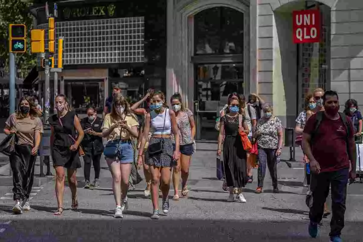 Diverses persones amb mascareta creuen un carrer de Barcelona