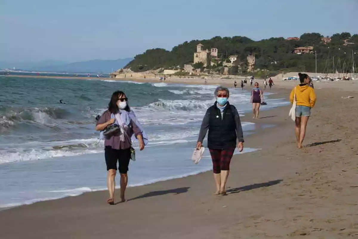 Pla general de dues dones amb mascareta caminant per la platja d'Altafulla en el primer dia permès per sortir a practicar esport