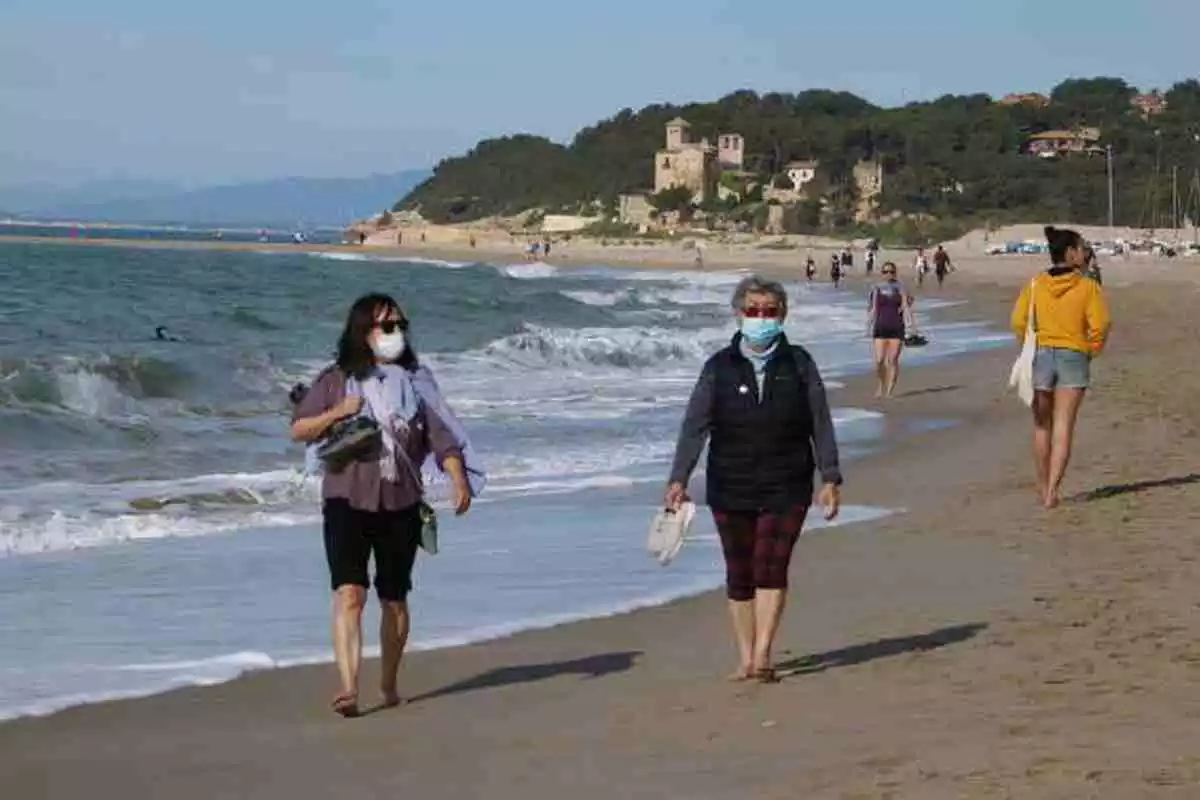 Pla general de dues dones amb mascareta caminant per la platja d'Altafulla en el primer dia permès per sortir a practicar esport
