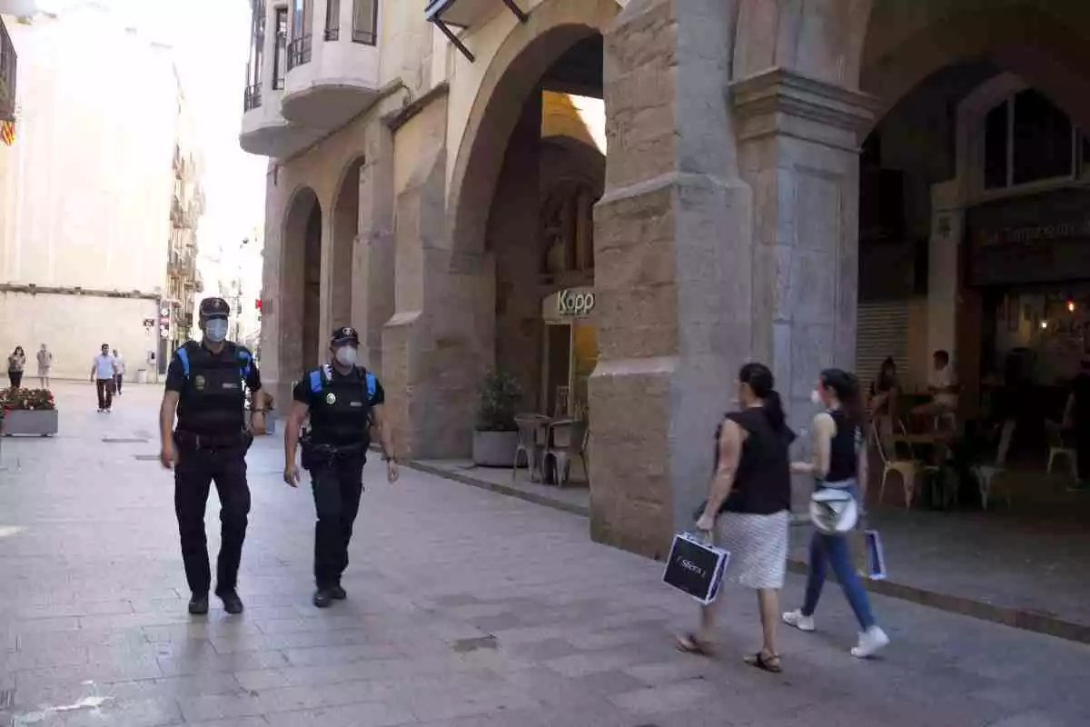 Agents de la Guàrdia Urbana patrullen pee l'Eix Comercial de Lleida per controlar que es compleixin les mesures de seguretat.
