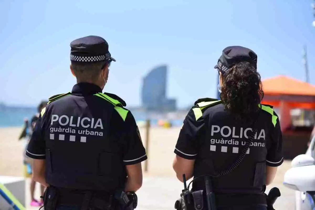 Dos agents de la Guàrdia Urbana de Barcelona d'esquena davant de la platja