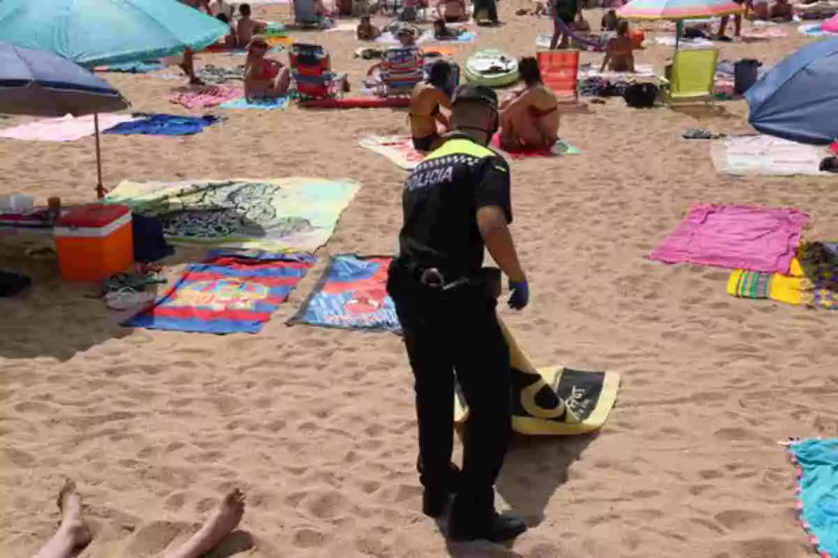 Un policia local retirant una de les tovalloles de la platja de Palafrugell