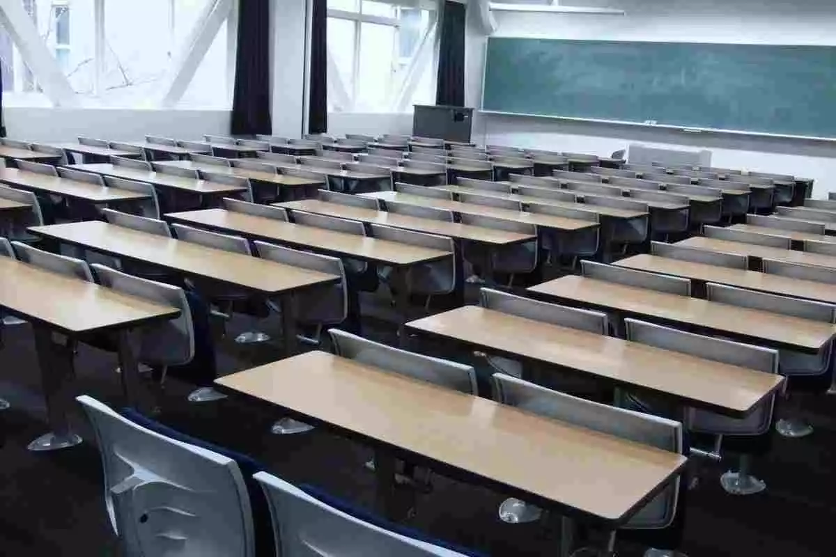 L'interior d'una aula amb taules, cadires i una pissarra