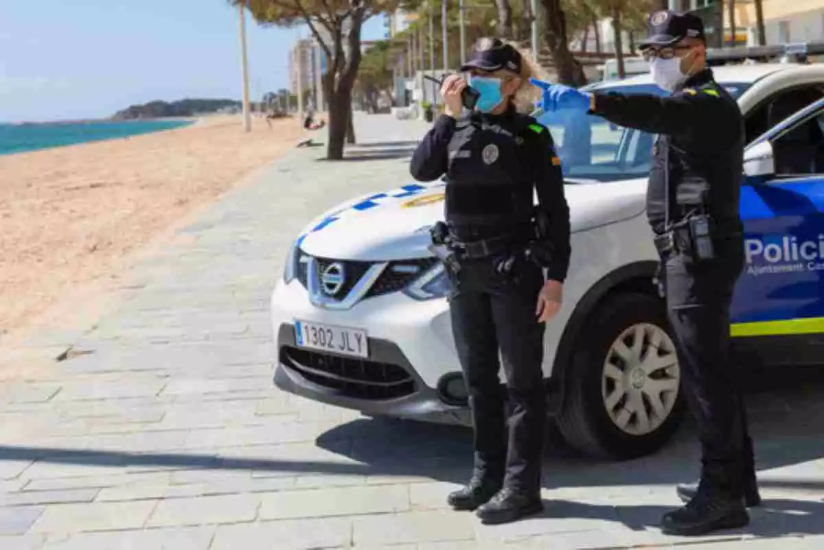 Dos agents de la policia local de Castelló-Platja d'Aro, davant del seu vehicle en una de les platges del municipi