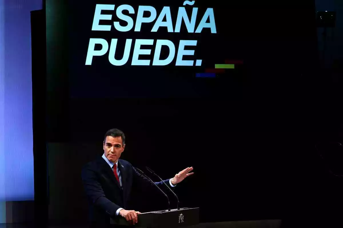 El president Pedro Sánchez amb la mà aixecada i el lema 'España Puede' darrere