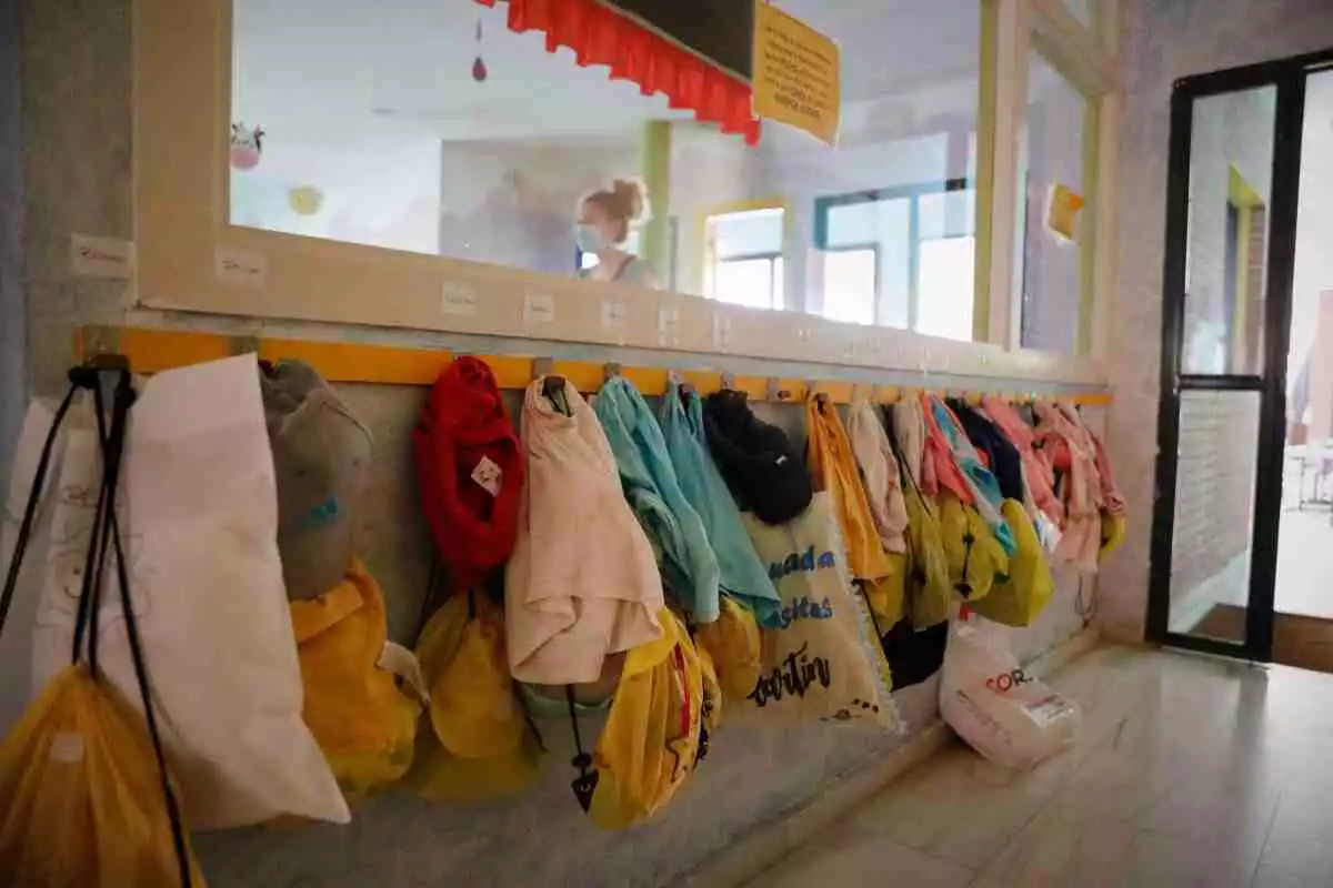 Imatge dels penjadors d'una llar d'infants, amb bosses, jaquetes i bates