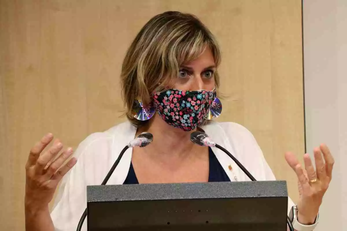 La consellera de Salut, Alba Vergés, amb les mans aixecades, mascareta a la boca i els micròfons davant