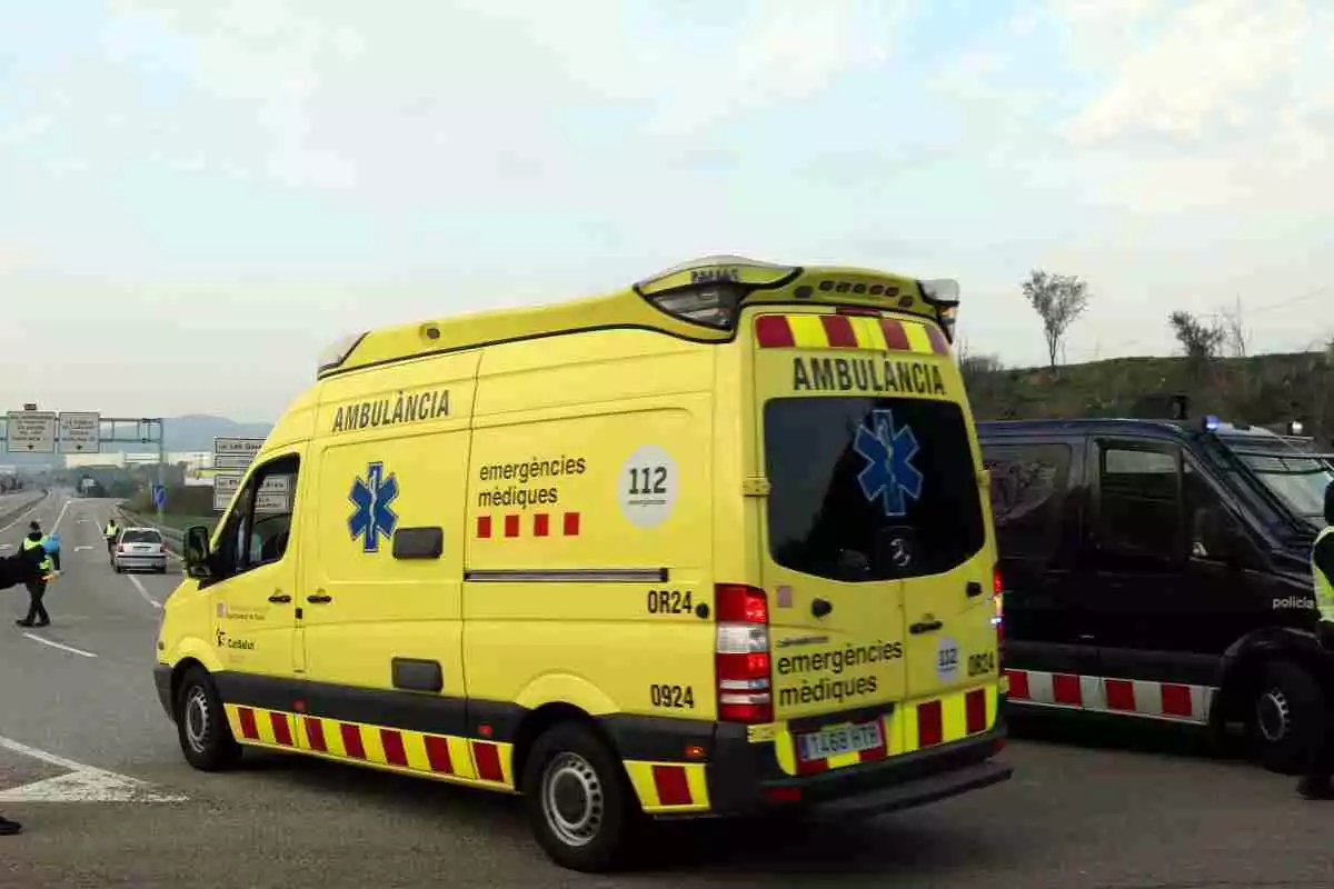 Una ambulància de color groc del Sistema d'Emergències Mèdiques (SEM) amb un cotxe dels Mossos al costat