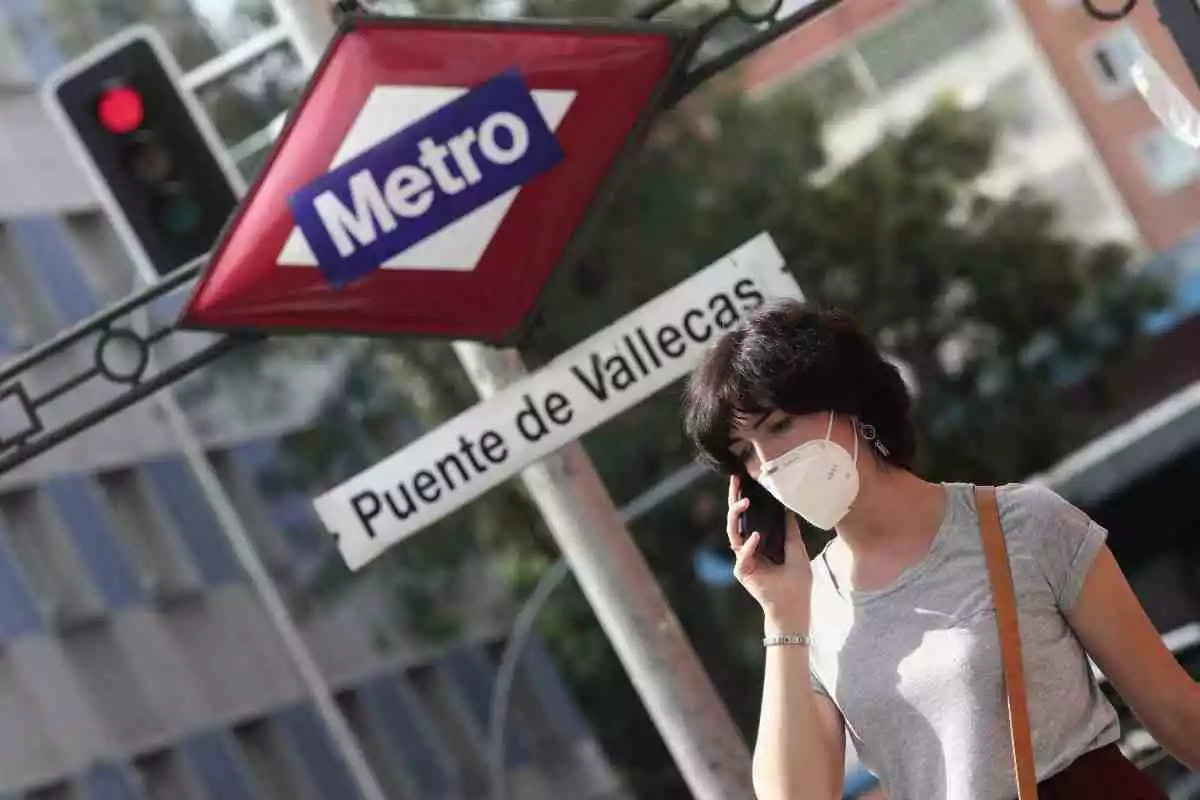 Una dona, parlant per telèfon, passa per davant de la parada de metro del districte madrileny de Puente de Vallecas