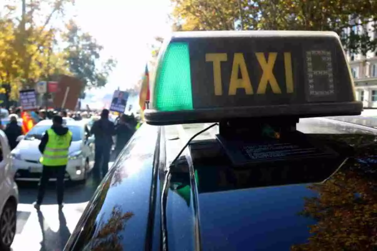 Una manifestació de taxistes amb un vehicle en primer pla amb llum verda encesa