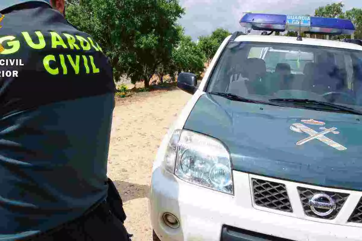 Agent de la Guàrdia Civil al costat d'un vehicle del cos policial