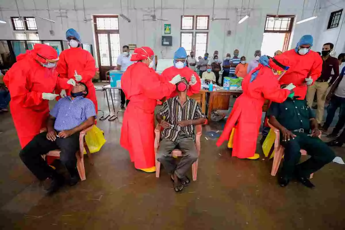 Diversos treballadors sanitaris, amb vestits vermells, fan proves PCR a tres homes a Sri Lanka