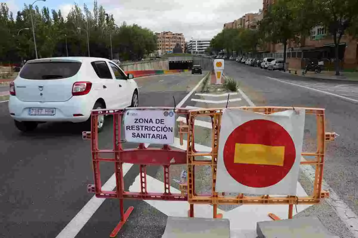 Imatge d'un vehicle passant pel costat d'un cartell que indica que accedeix a una zona de restricció sanitària