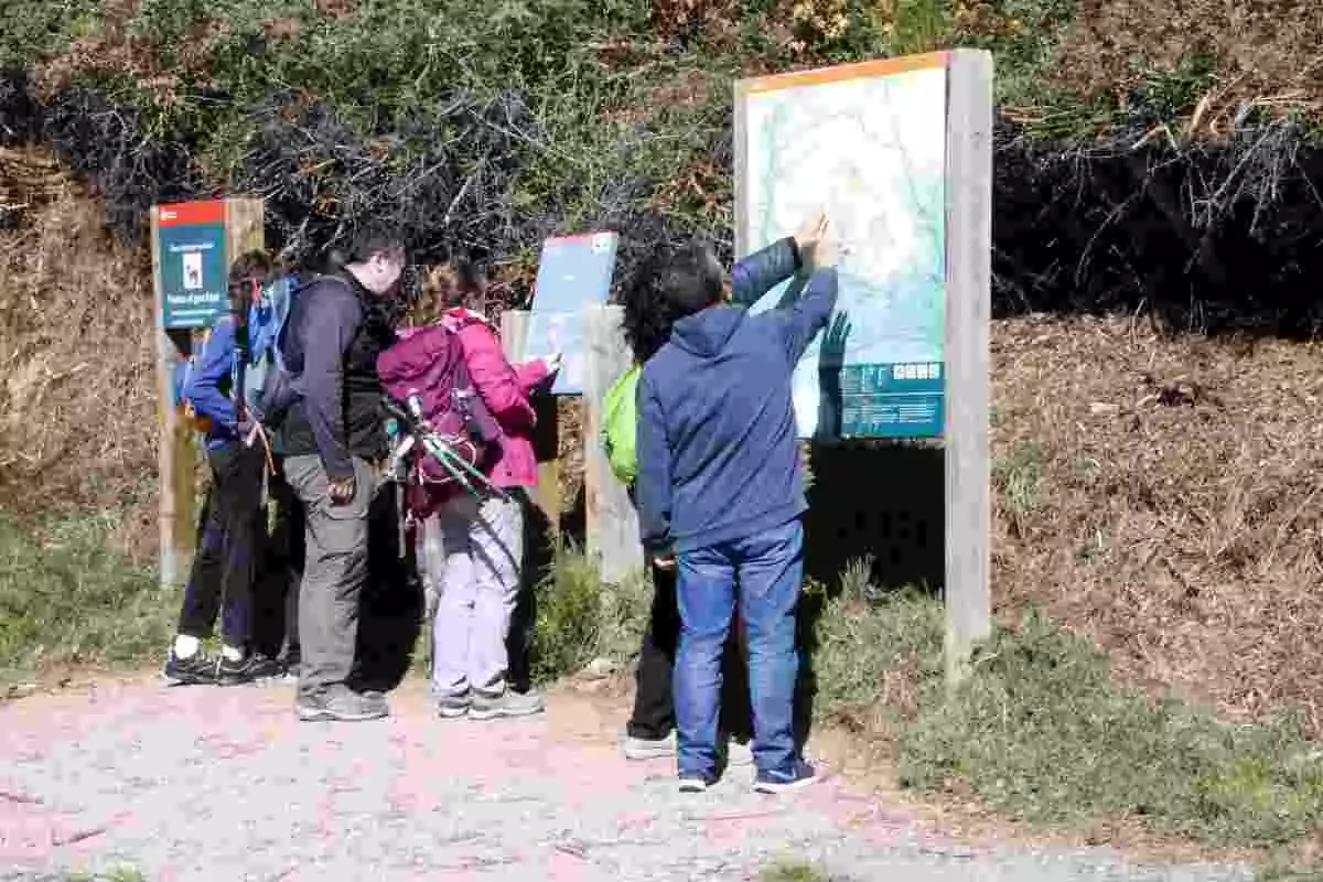 Pla general de visitants observant un cartell a la zona de Collformic del Parc Natural del Montseny