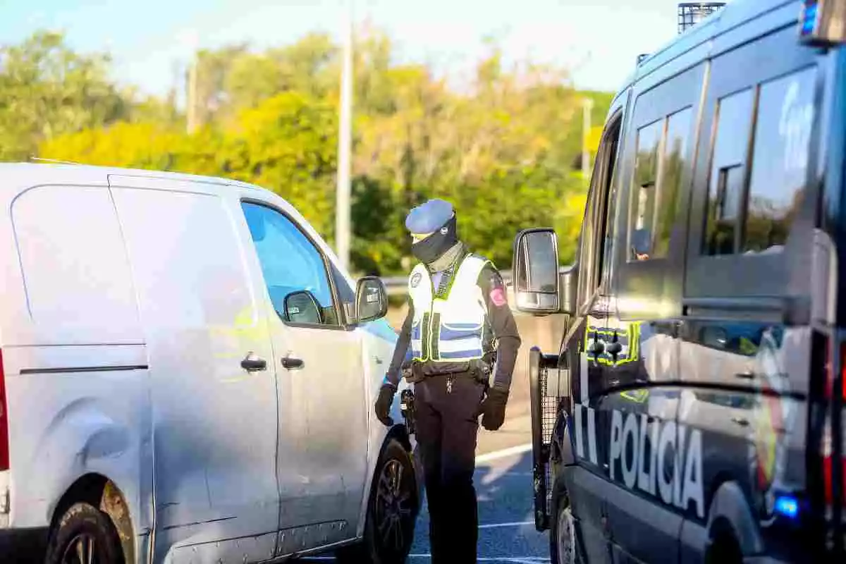 Un agent de la Policia Nacional revista una furgoneta de color blanc en un control policial