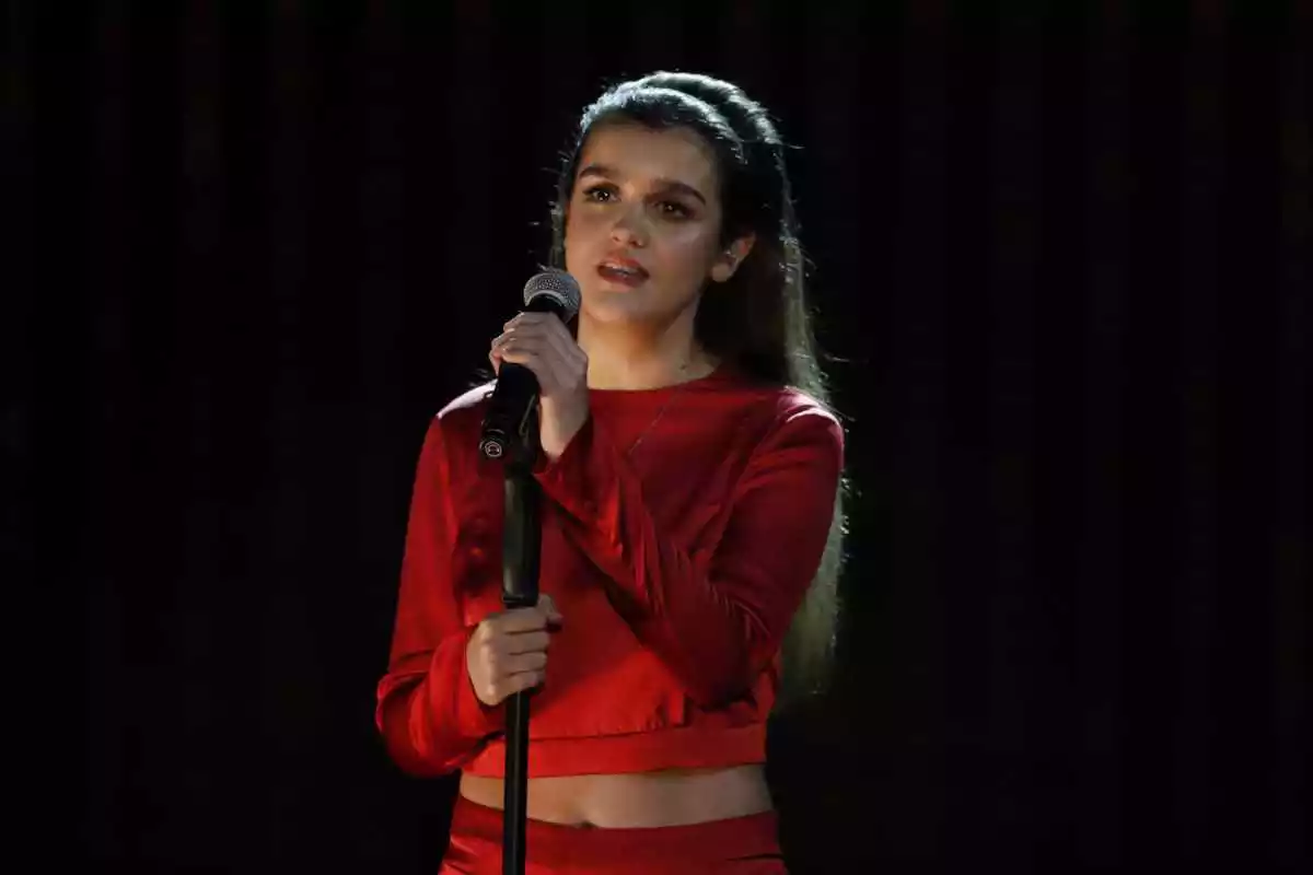 Amaia Romero vestida de vermell amb el micro a la mà dalt d'un escenari