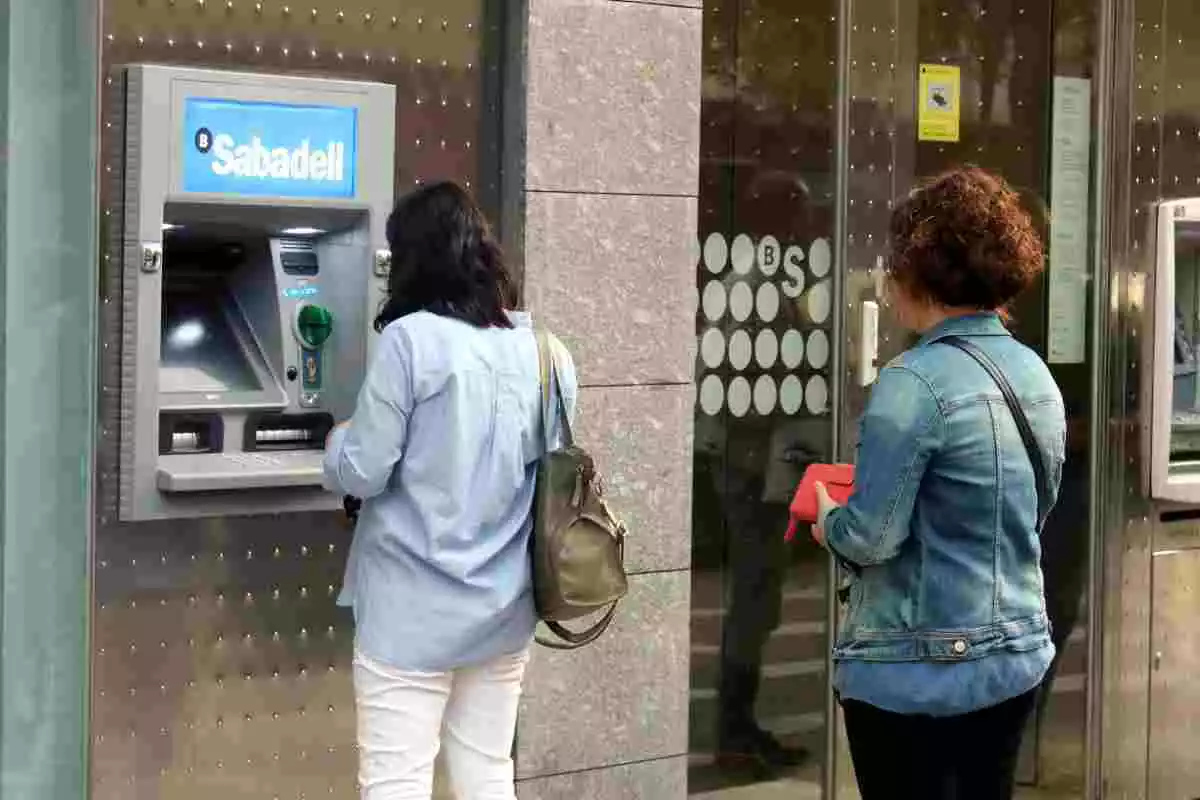 Dues dones retirant diners a la sucursal que el Banc Sabadell té a Girona