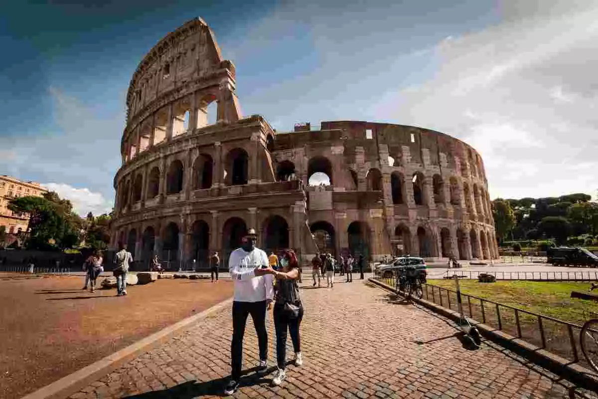 Imatge de dues persones amb mascareta, davant del Coliseu de Roma