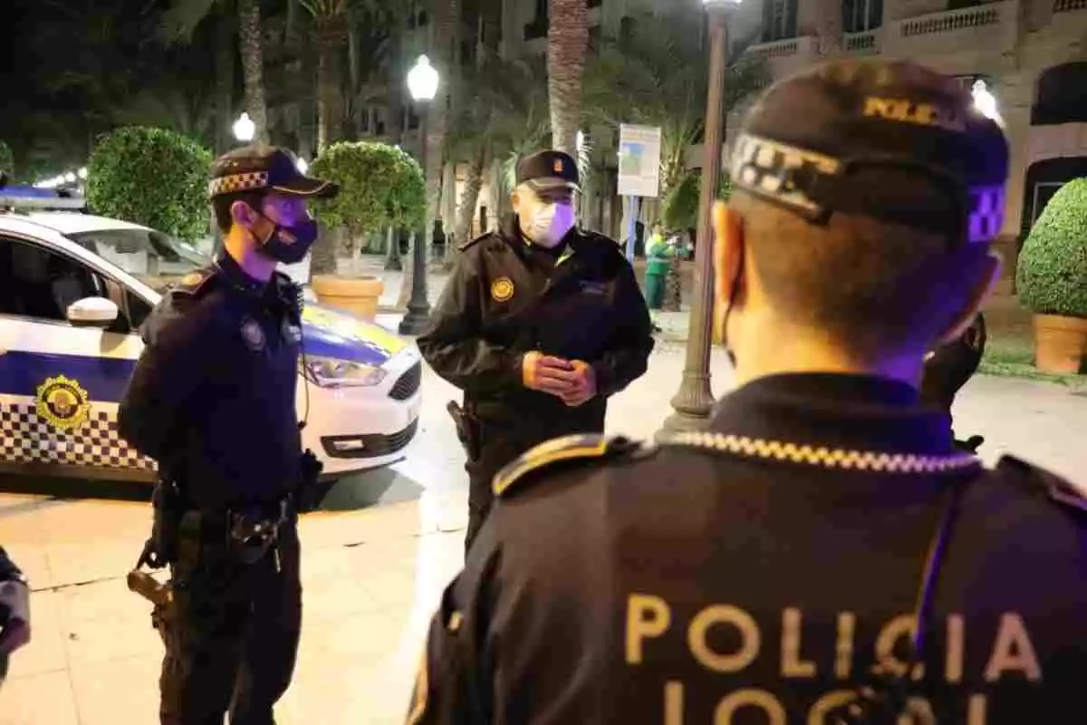 Tres agents de la Policia Local d'Alacant amb un vehicle policial al darrere