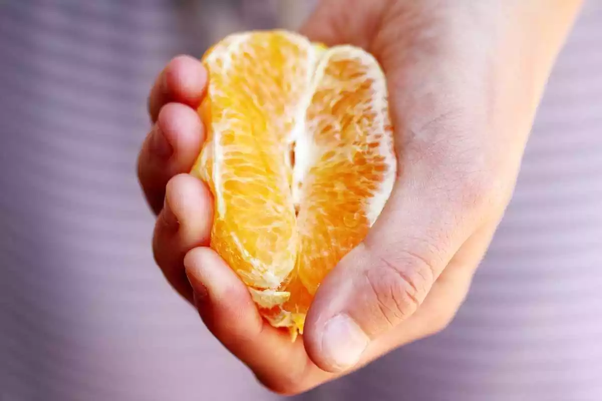 Un mà aguantant una mitja taronja pelada