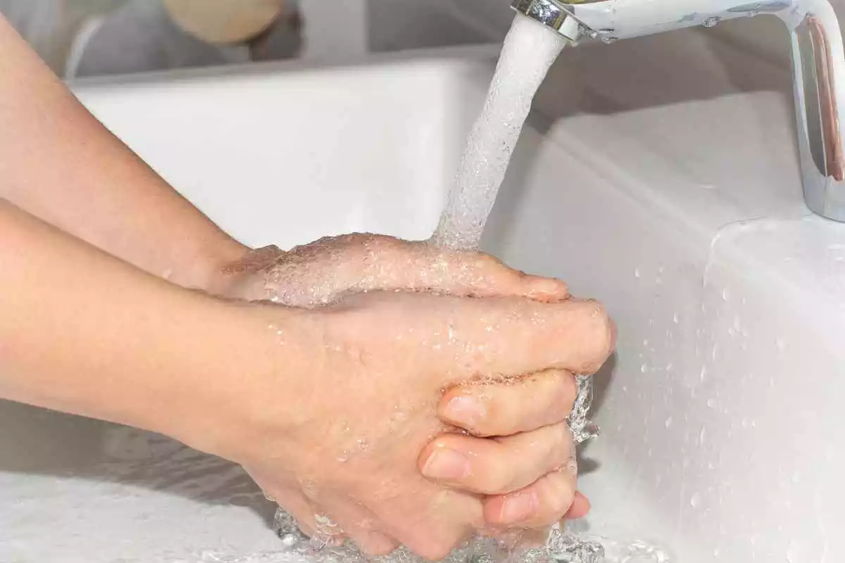 Una persona es renta les mans en una aixeta d'aigua oberta