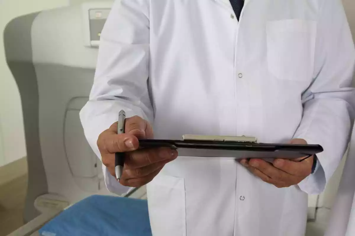 Imatge d'un doctor amb carpeta i bolígraf a la mà durant una prova mèdica