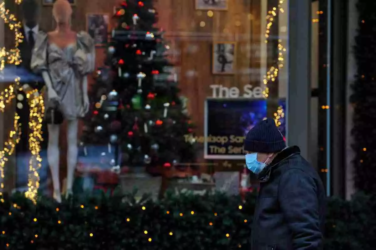 Un home amb mascareta passant per davant d'un arbre de Nadal i decoració diversa
