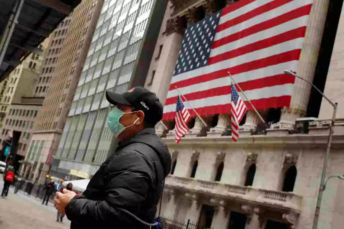 Un home porta mascareta davant la Borsa de Nova York, als Estats Units