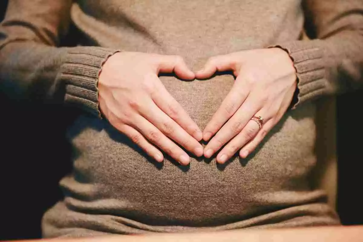 Una dona embarassada fent la forma del cor amb les seves mans sobre la panxa
