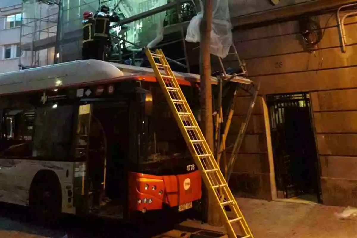 Un dels autobusos implicats en la topada, a sota d'una bastida a l'encreuament dels carrers de la França Xica i de Radas de Barcelona. Imatge cedida el 30 de gener del 2021