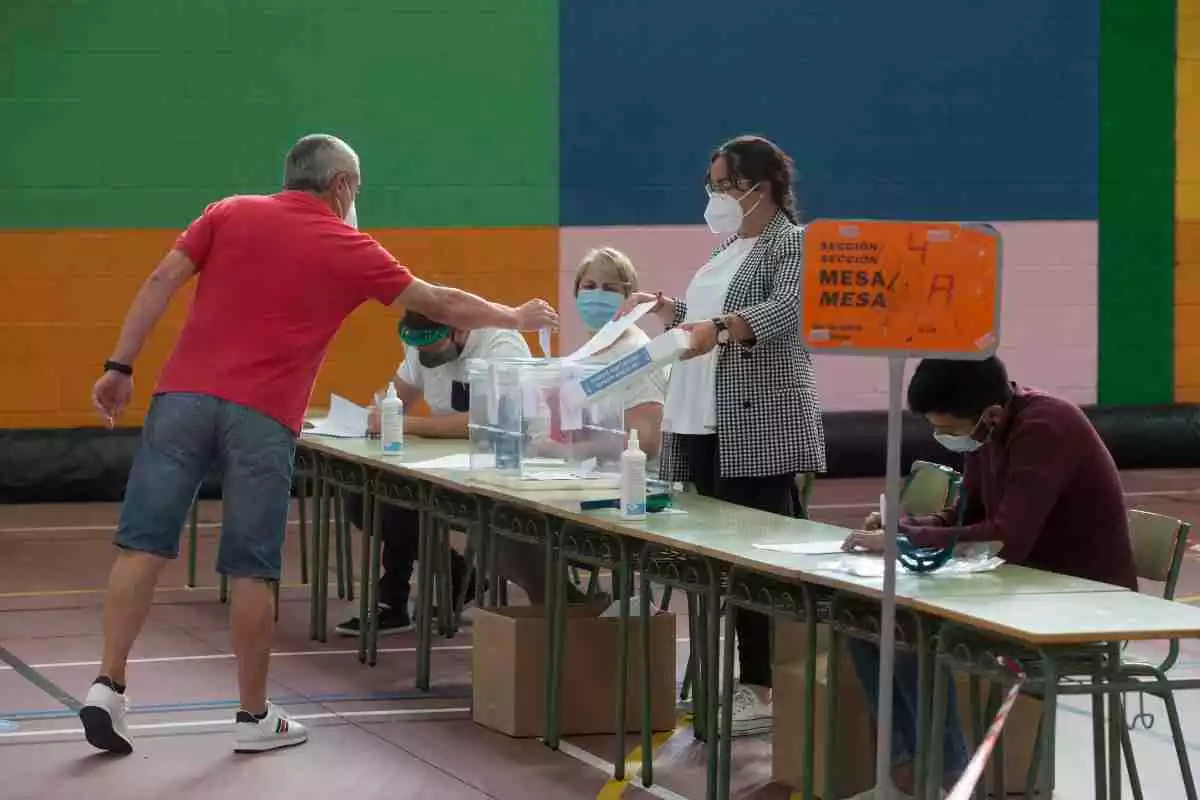 Un home, amb samarreta vermella, introdueix el seu vot a l'urna durant les eleccions gallegues del passat mes de juliol