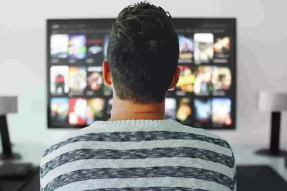 Un noi mirant una Smart TV amb molts programes per a escollir
