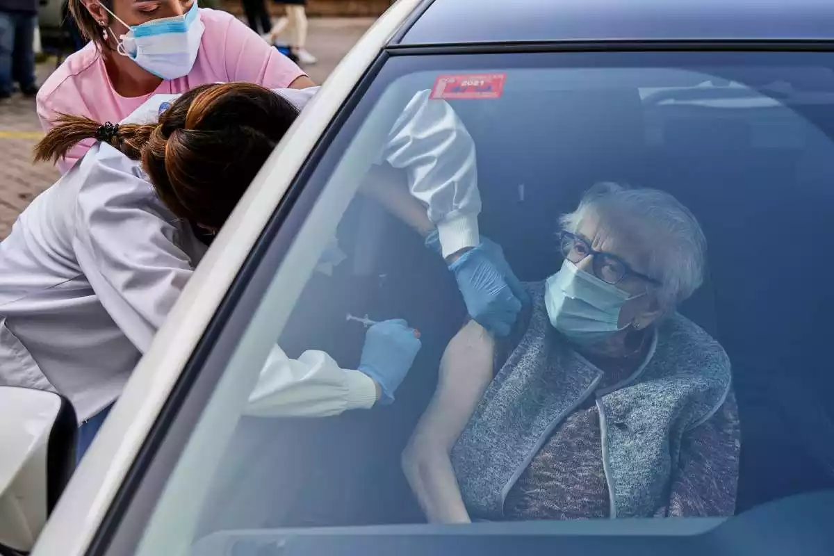 Una dona gran rebent una dosi de la vacuna de la Covid-19 sense sortir del cotxe