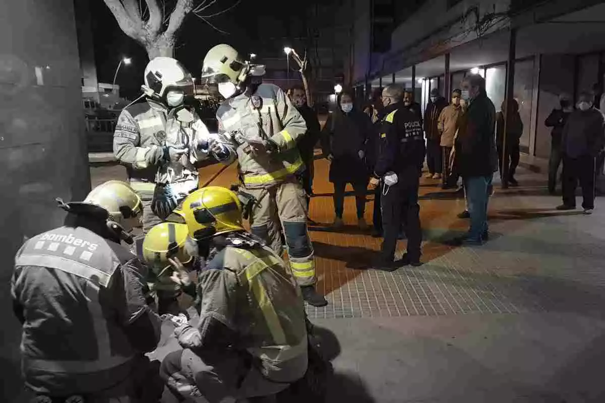 Bombers treballant en el desallotjament d'un bloc de pisos