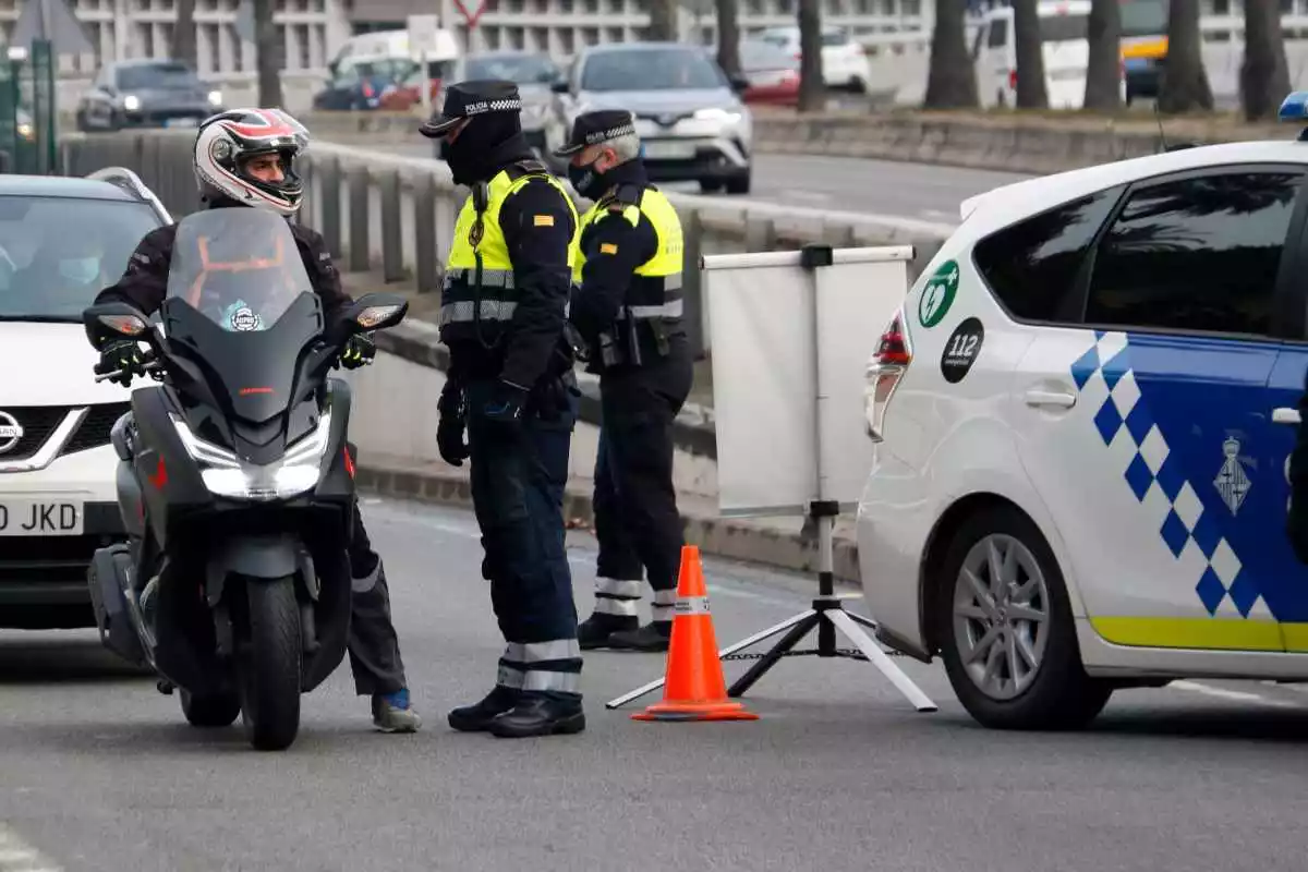 Dos agents de la Guàrdia Urbana de Barcelona parlant amb un motorista en un control policial