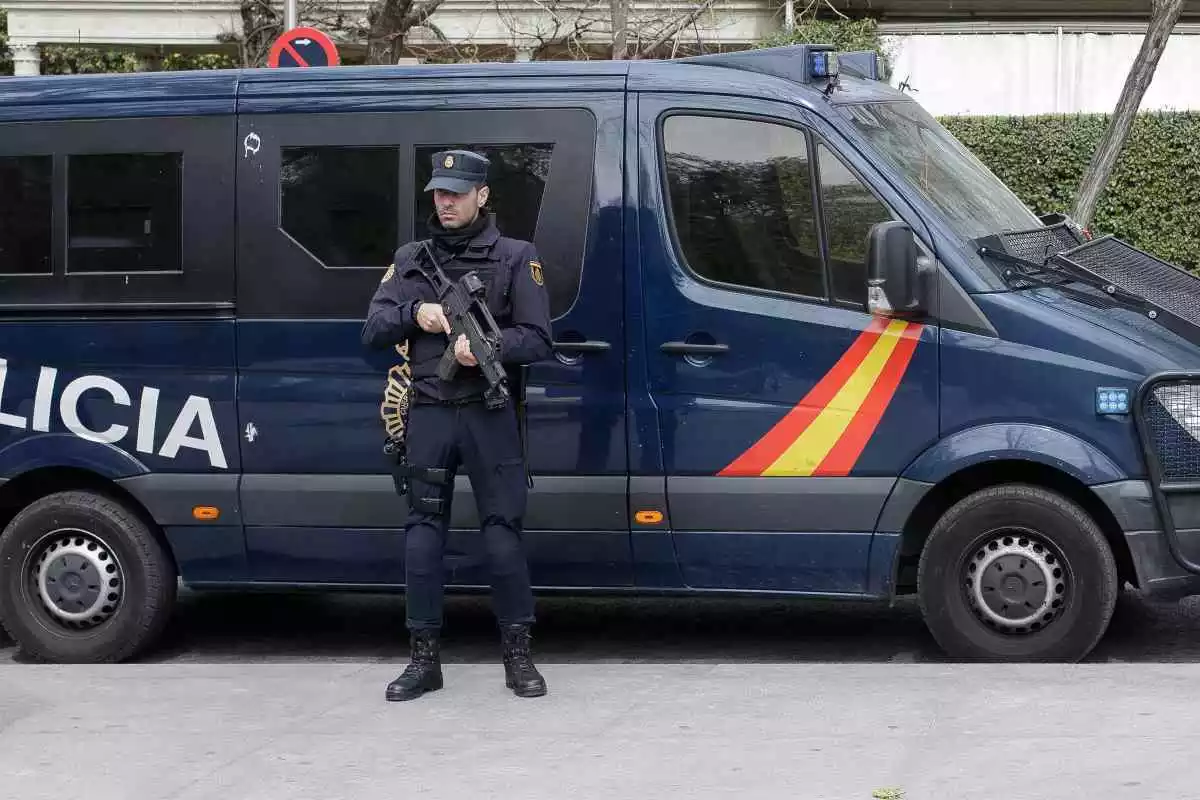 Imatge d'un agent de la Policia Nacional, amb una arma a les mans, davant una furgoneta